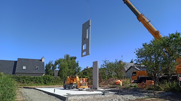 Pose à la grue d'un mur intérieur préfabriqué sur la dalle.