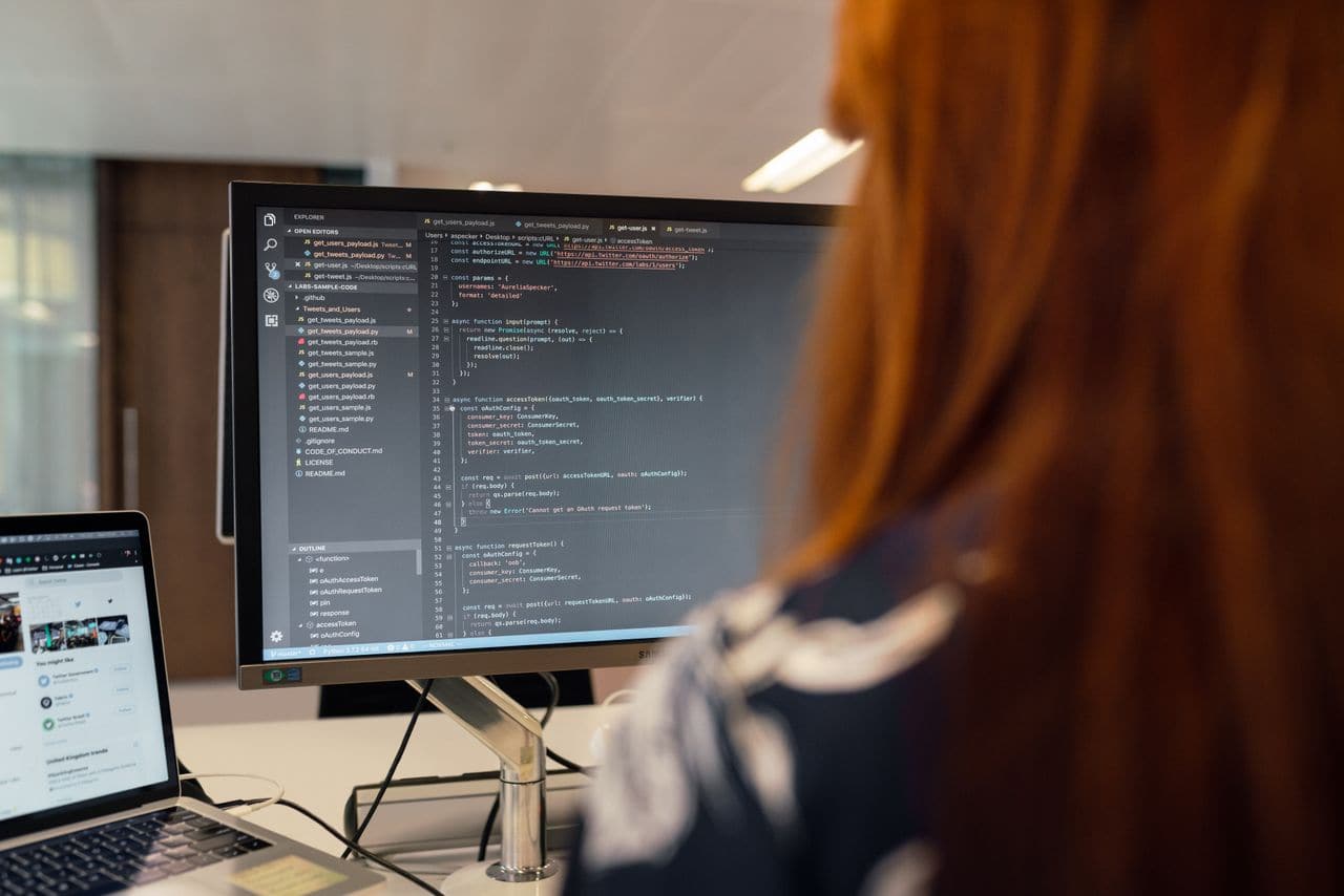 Développeuse de dos face à un écran rempli de code — exactement ce que vous ne saurez pas juger, et ce n'est pas grave : ce qui se juge, c'est la relation.