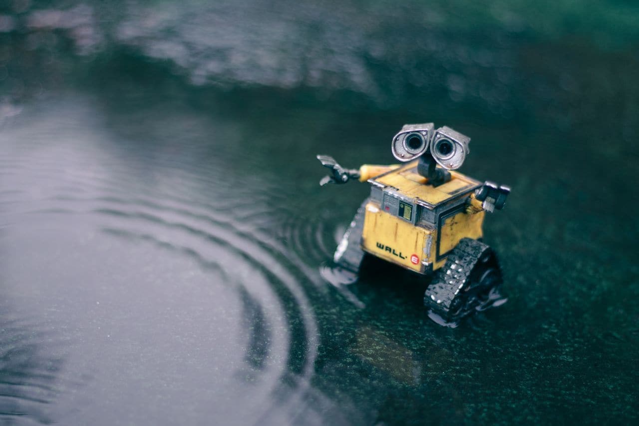 Figurine de robot seule au milieu d'une flaque d'eau, tendant le bras — une seule figure pour porter deux rôles.