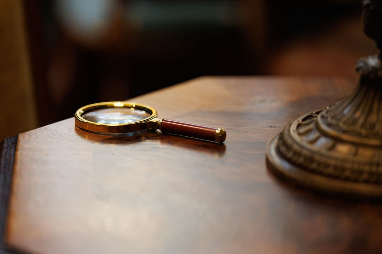 Loupe posée sur un bureau en bois sombre — l'examen d'une due diligence, qui ne cherche pas la beauté du code mais à qui il appartient.