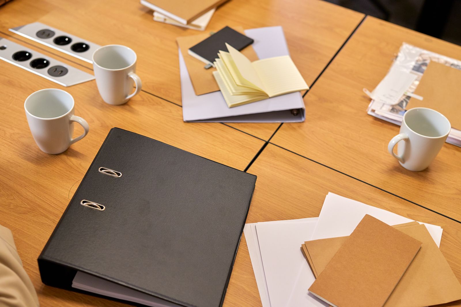 Bureau ordonné : classeurs, feuilles et tasses de café disposés avant une réunion.