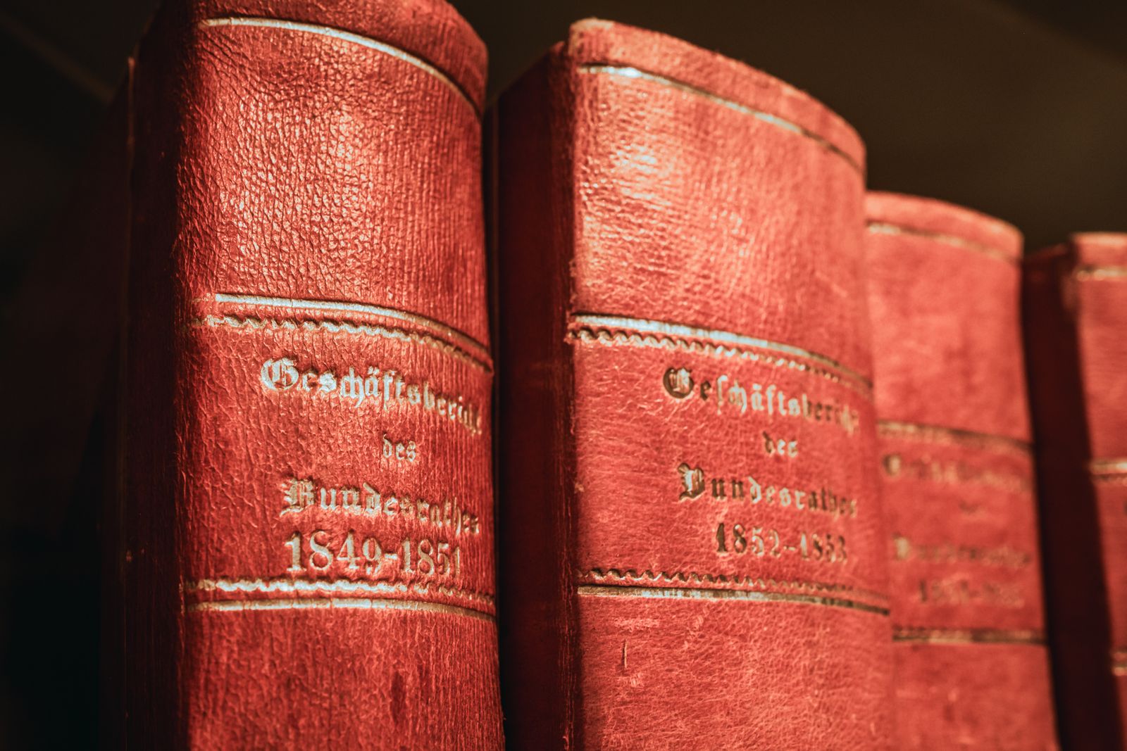 Rangée de recueils législatifs anciens reliés de cuir rouge sur les étagères d'une bibliothèque.