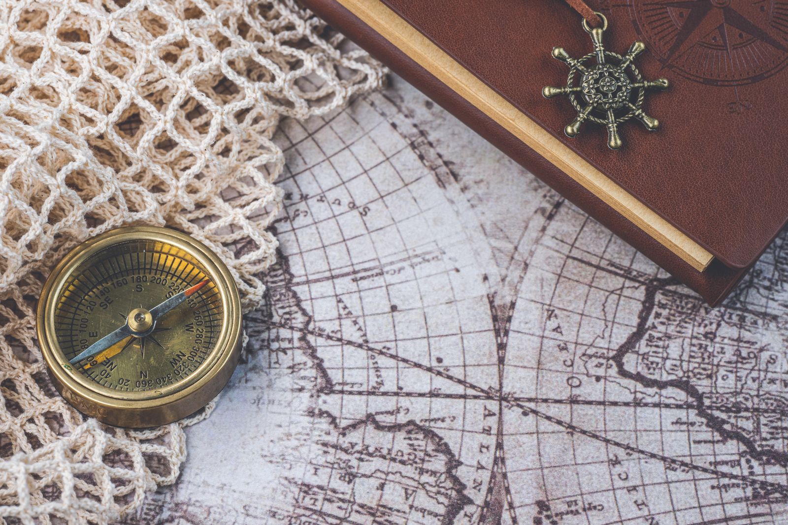 Boussole ancienne et carnet de cuir posés sur une carte marine dépliée.