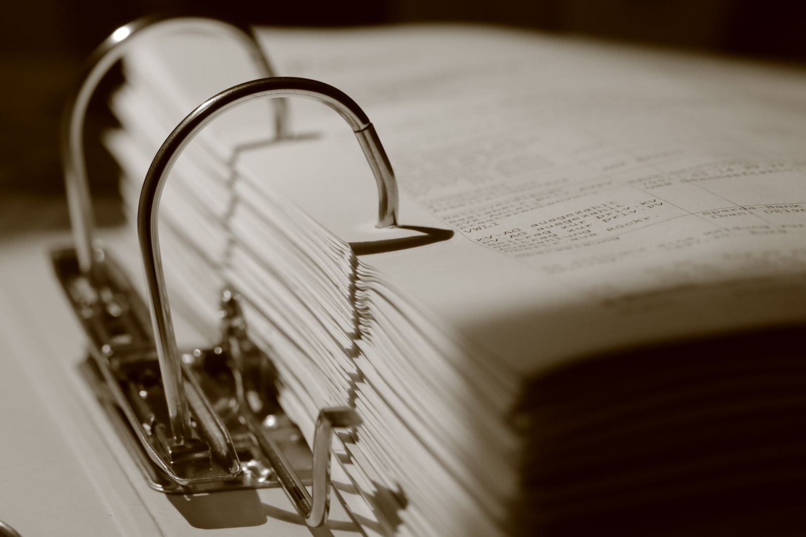 Gros plan sépia sur un classeur rempli de documents administratifs.