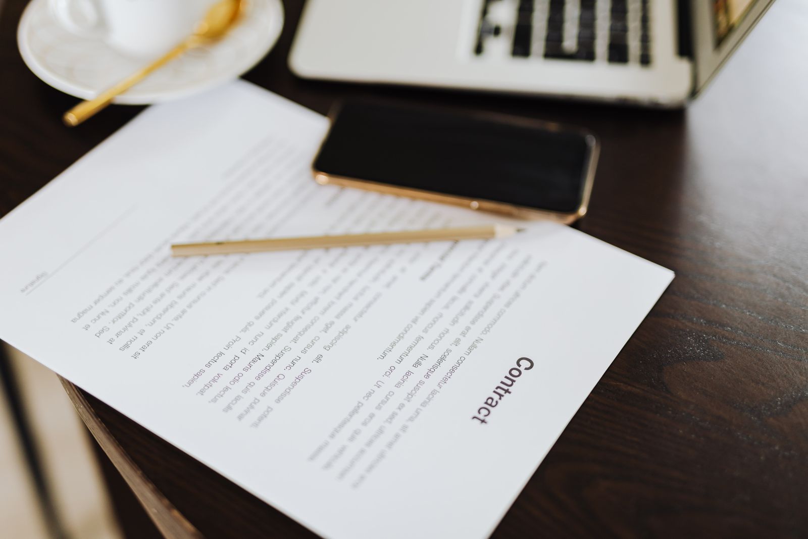 Contrat imprimé posé sur un bureau, à côté d'un ordinateur portable et d'une tasse de café.