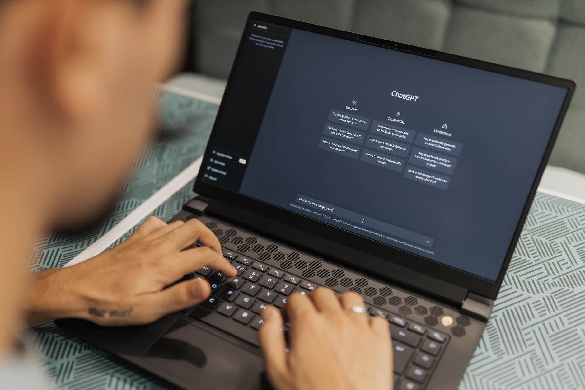 Personne tapant sur un ordinateur portable affichant la page d'accueil de ChatGPT.