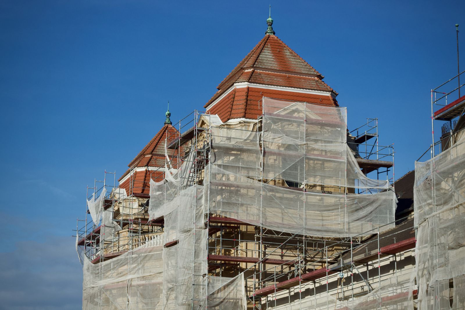 Bâtiment ancien en cours de restauration, entièrement couvert d'échafaudages et de filets de protection.