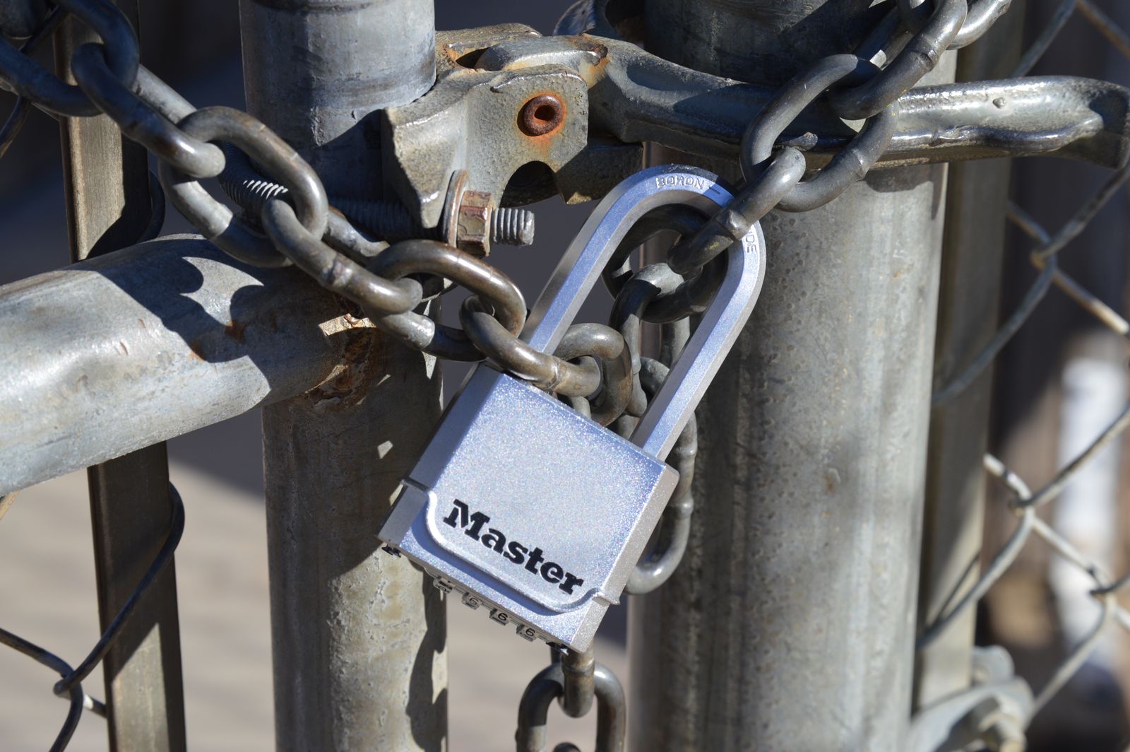 Portail métallique gris fermé par une chaîne et un cadenas.